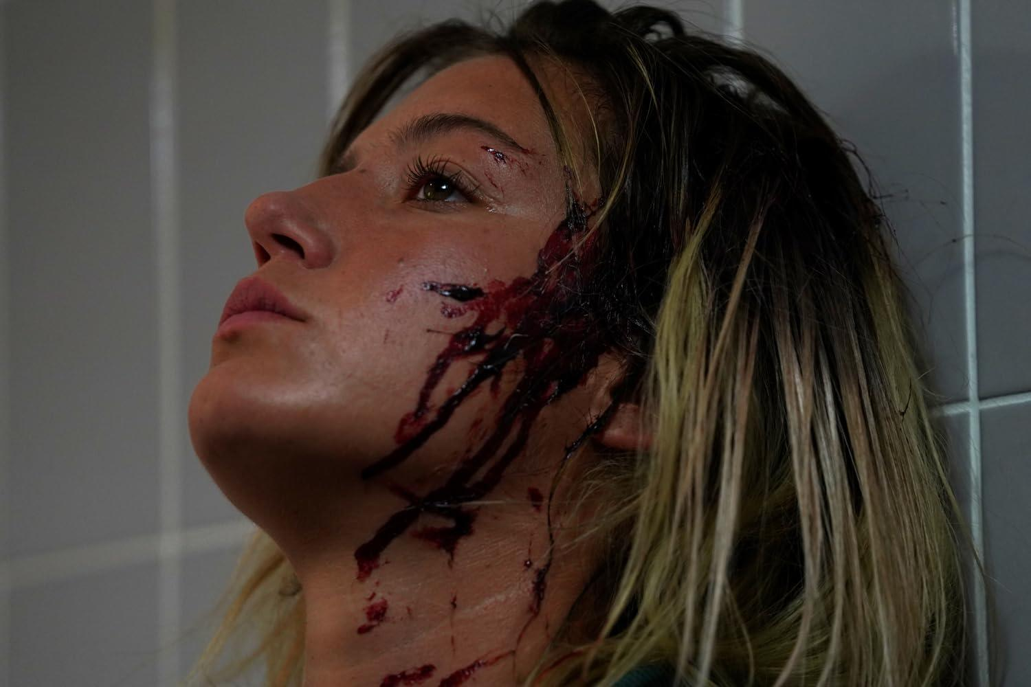 Nahaufnahme einer Frau mit Blut im Gesicht und am Hals. Sie schaut nach oben.