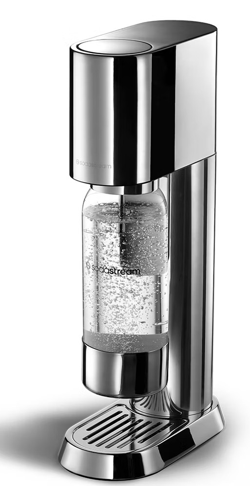 Chromowany SodaStream. W środku przezroczysta butelka z bąbelkami. Maszyna jest błyszcząca i pionowa.