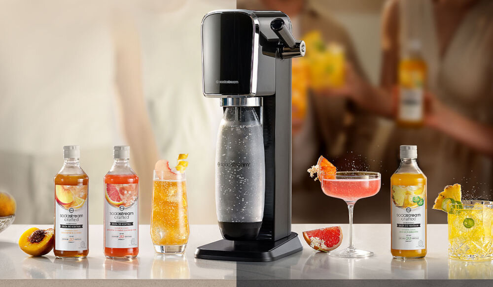 Konfiguracja SodaStream z butelkami i szklankami wypełnionymi kolorowymi napojami. Brzoskwinia, grejpfrut i inne smaki.