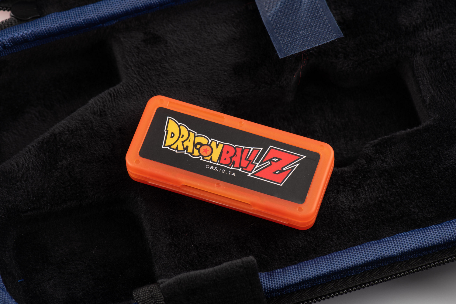 Una funda naranja de cartucho de juego de Dragon Ball Z dentro de una funda azul y negra.