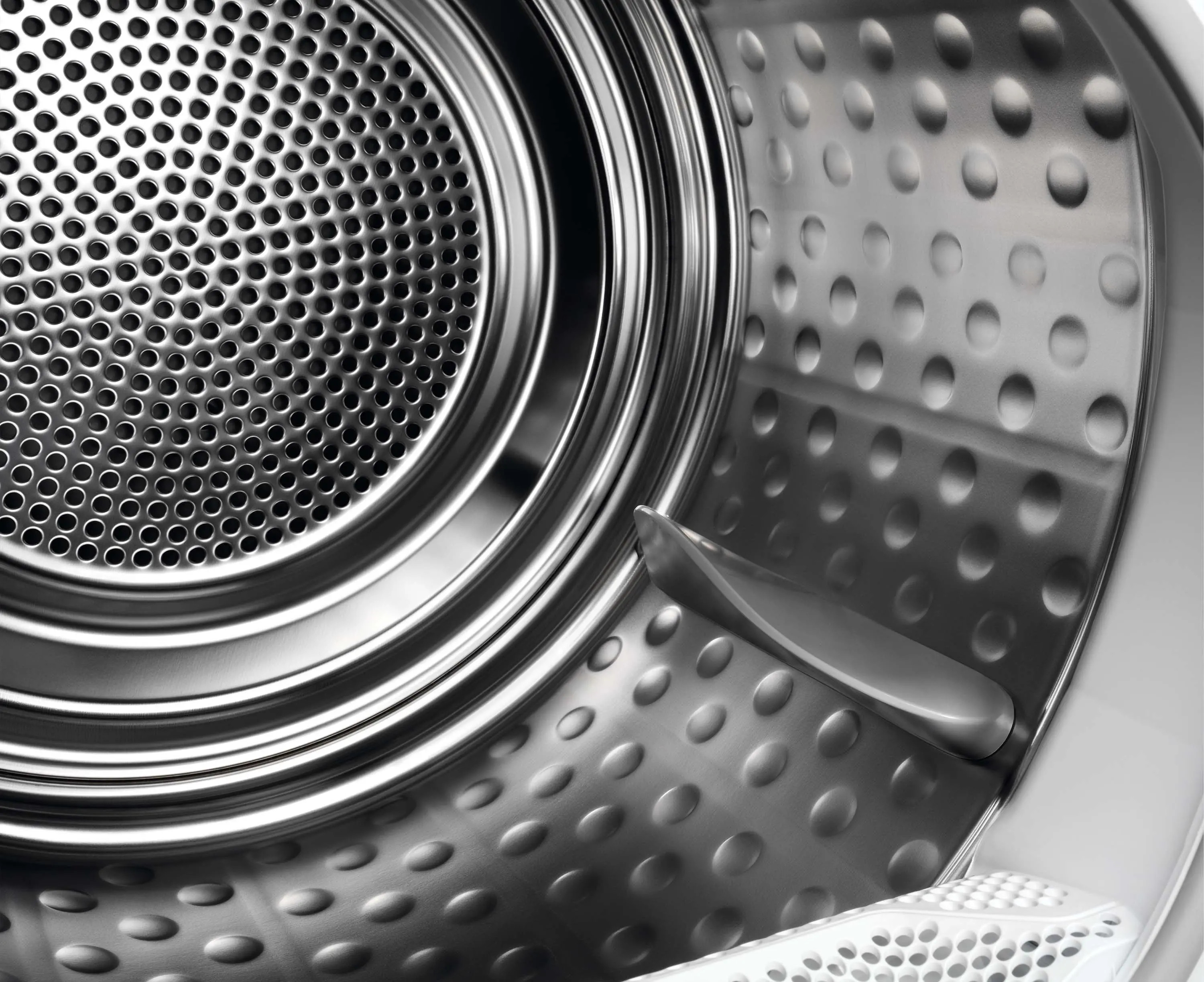 Wnętrze srebrnego bębna suszarki, z perforowanym metalowym tyłem i zakrzywionym ramieniem do suszenia.