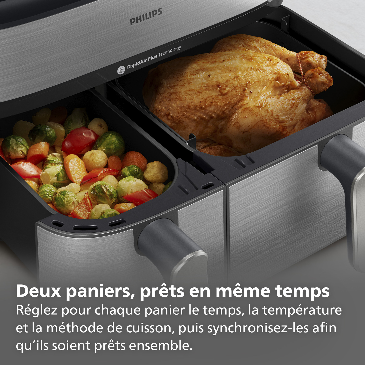 Friteuse à air avec poulet et légumes cuits dans des compartiments séparés. Design métallique, logo Philips.