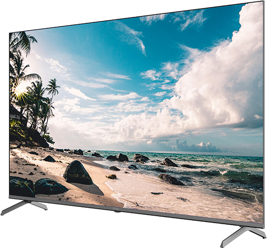 Egy nagyméretű TV egy tengerparti jelenetet jelenít meg kék éggel és óceánnal. A TV ezüst lábakkal rendelkezik.