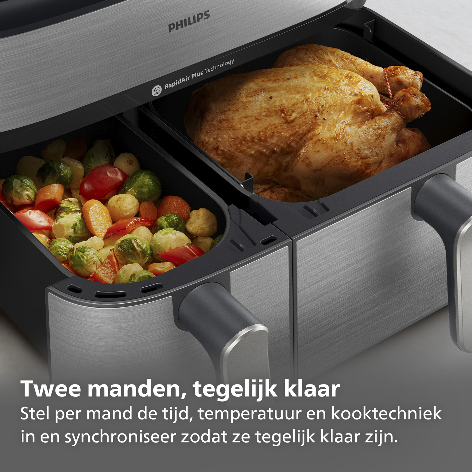 Philips airfryer met twee compartimenten, één met gebraden kip, de andere met groenten.