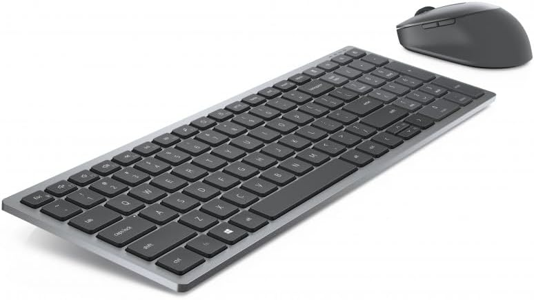 Un teclado plateado y un ratón gris, ambos sobre una superficie blanca.