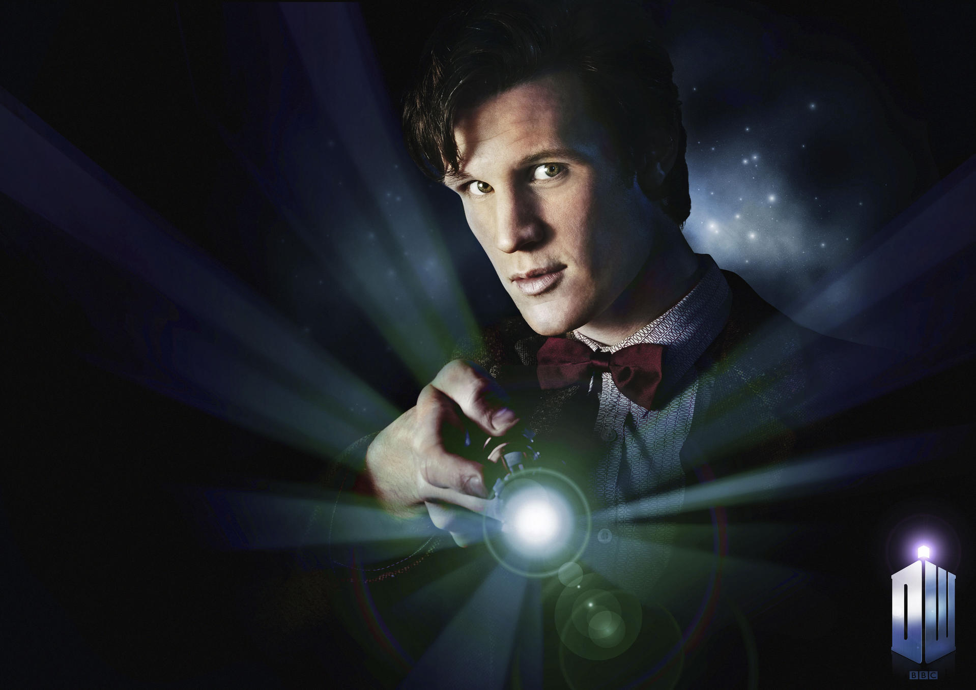 Mann hält Gerät, strahlt Licht aus. Dunkler Hintergrund mit Doctor Who Logo.
