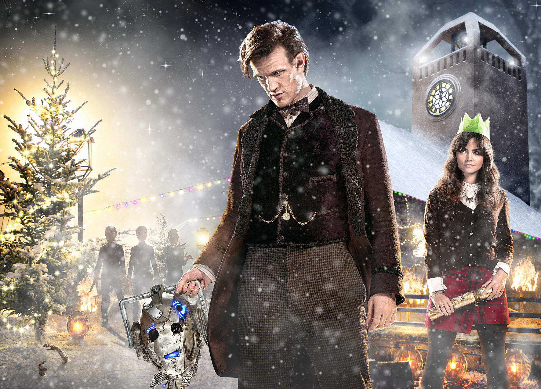 Doctor Who und Begleiter in einer verschneiten Szene. Weihnachtsbaum, Gebäude und Schnee.