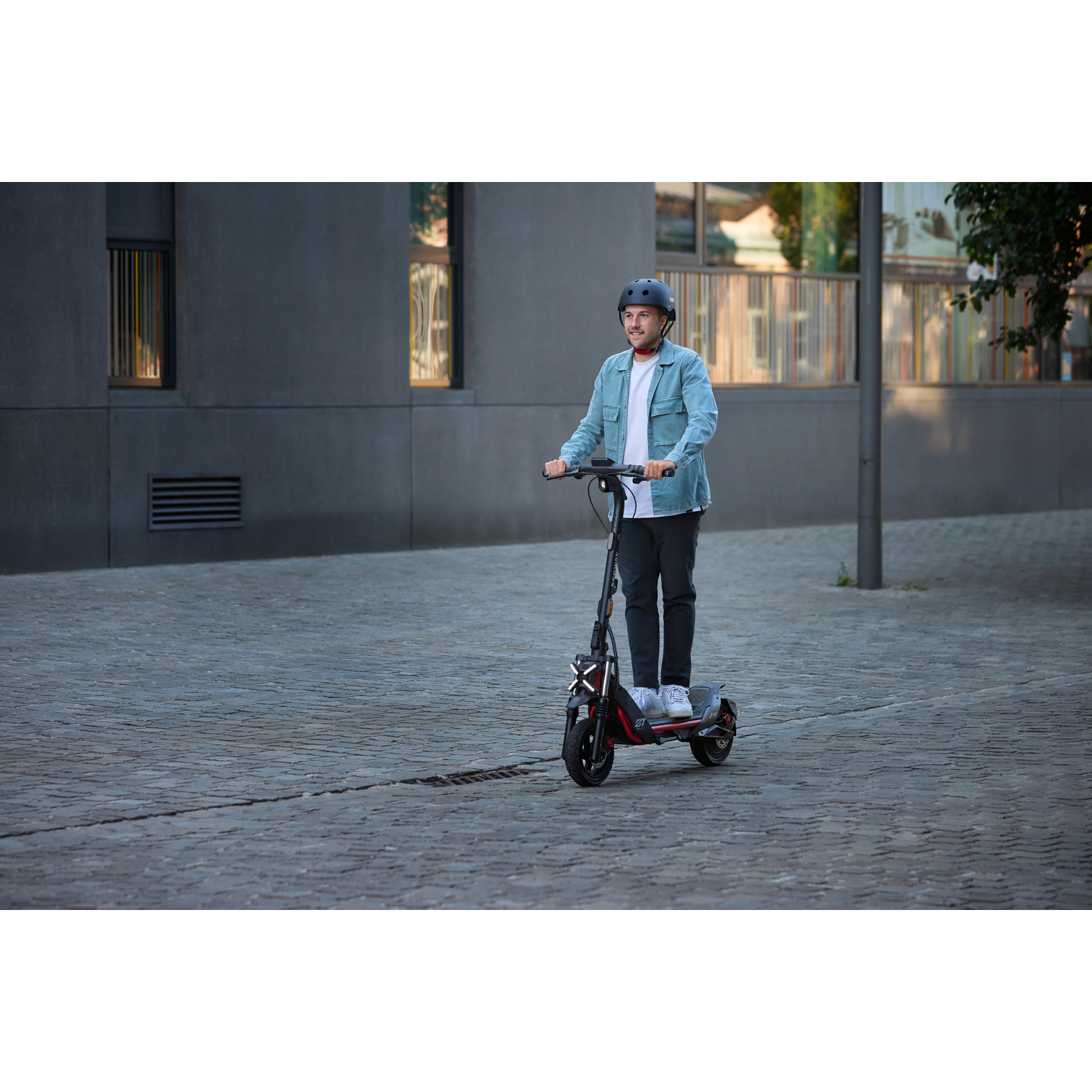 Un homme conduisant une trottinette électrique dans une rue.