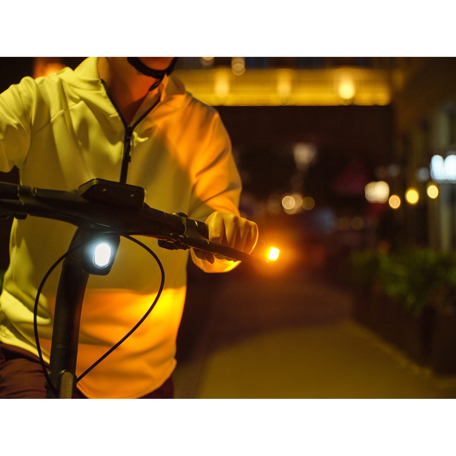 Une personne en scooter la nuit avec un phare et des clignotants oranges.