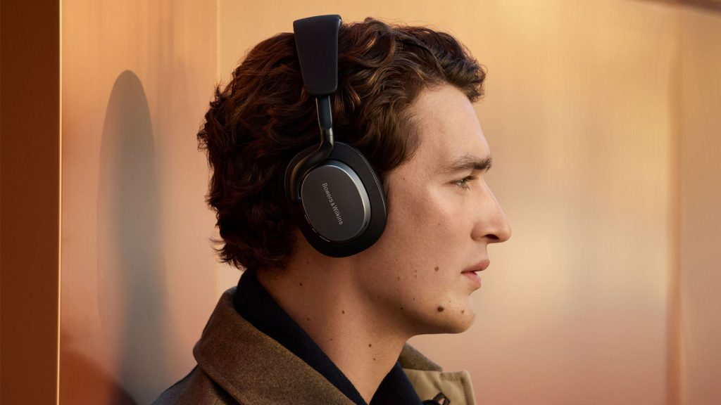 Mężczyzna w słuchawkach, w profilu, na pomarańczowym tle.