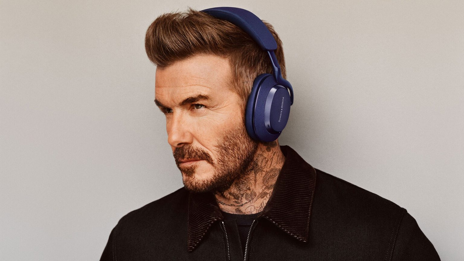 David Beckham z niebieskimi słuchawkami, portret, szare tło.