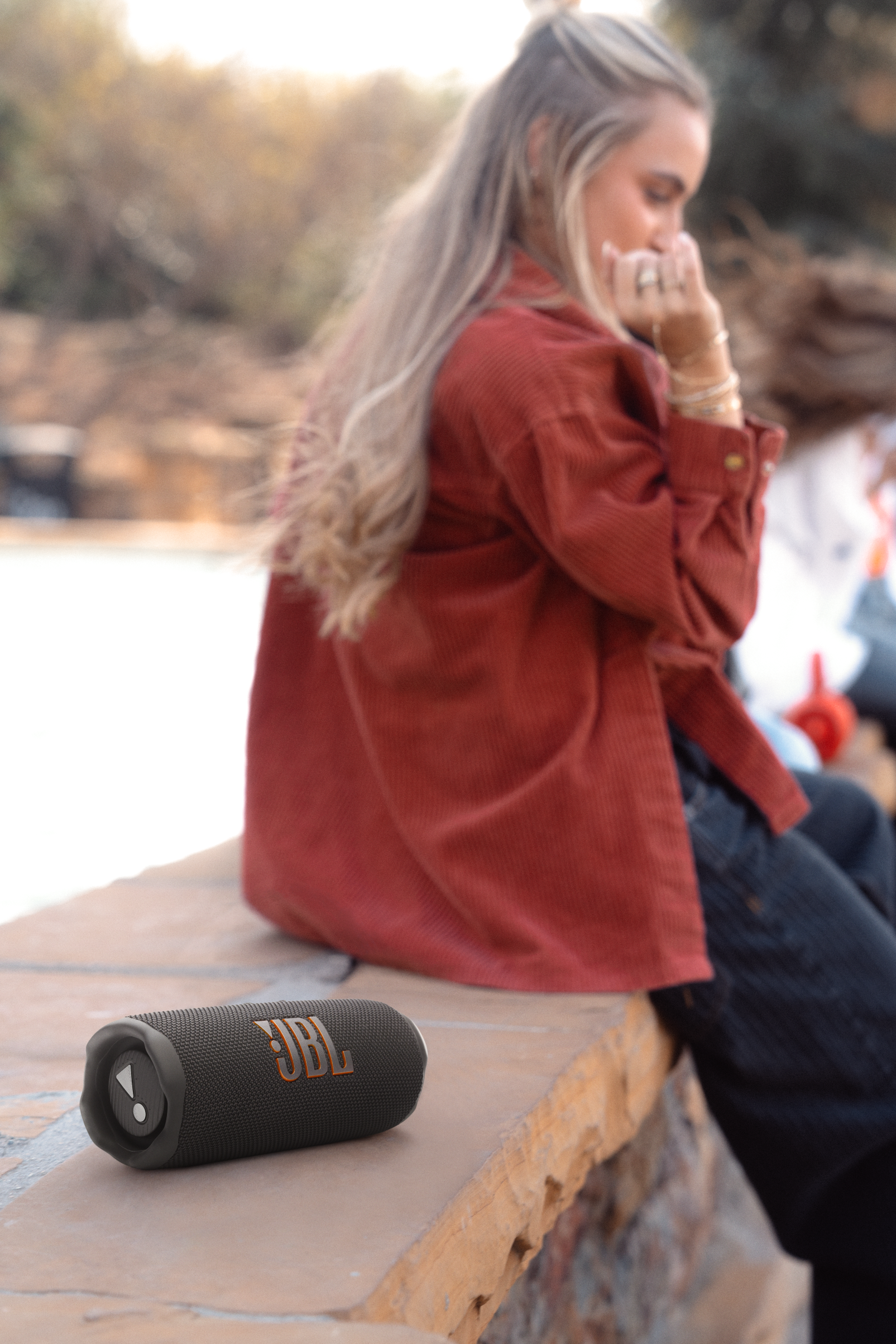 Bir çıkıntı üzerinde JBL hoparlör. Arka planda bir kadın oturuyor.