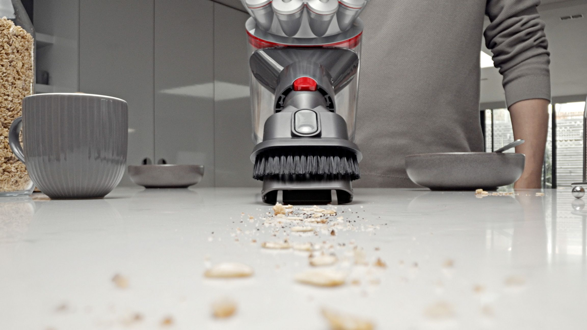 Aspirateur à main nettoyant les miettes sur une surface blanche.