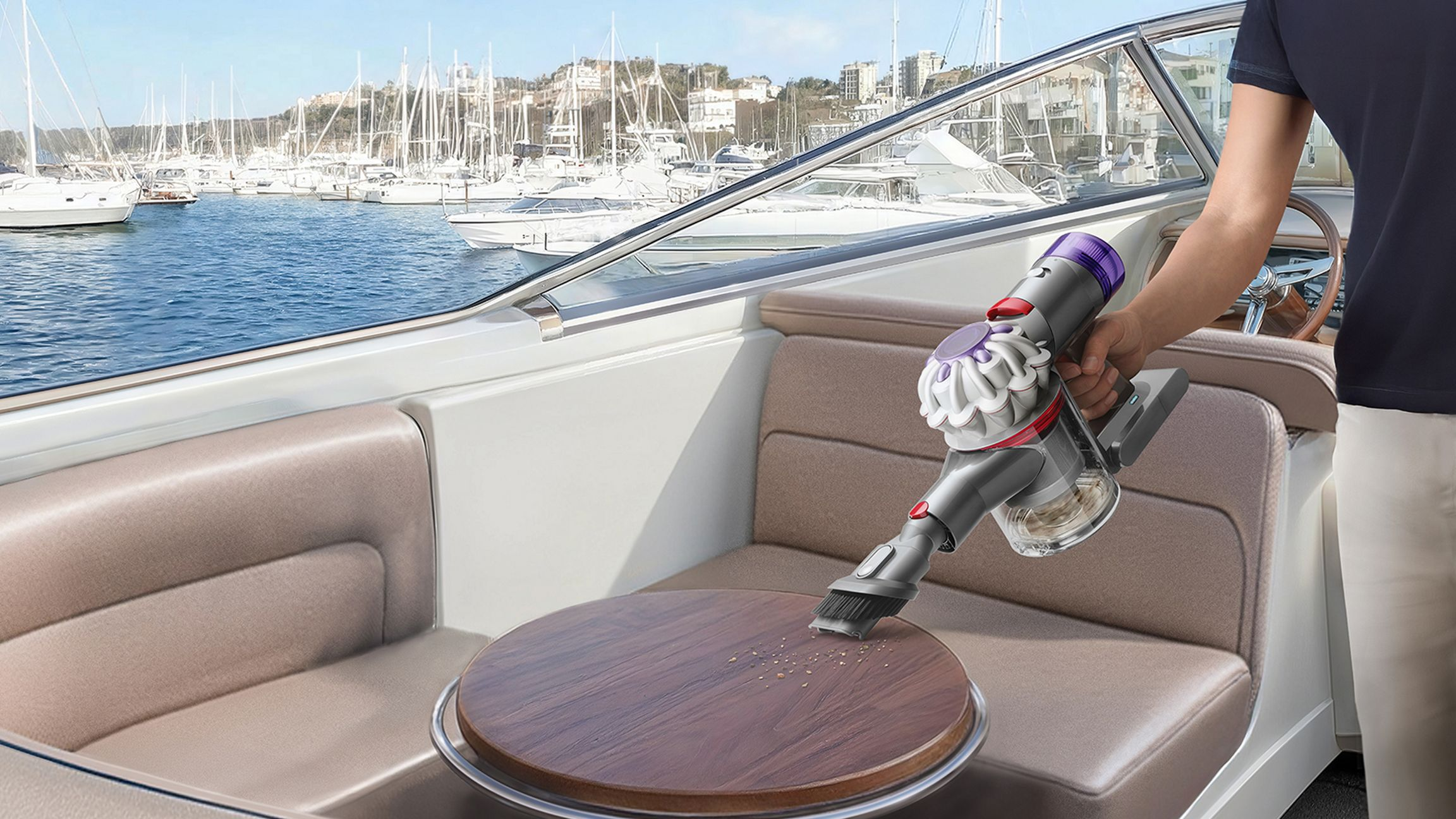 Personne passe l'aspirateur sur une table en bois sur un bateau avec un aspirateur à main.