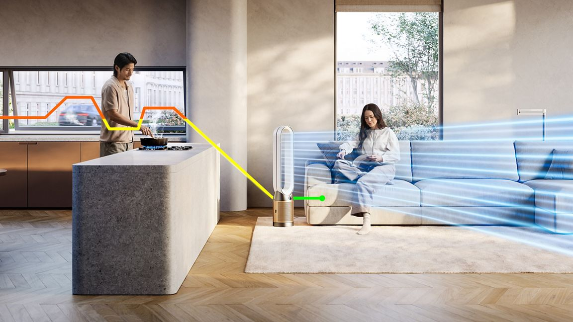 Scène d'intérieur avec un homme cuisinant et une femme utilisant un purificateur Dyson.