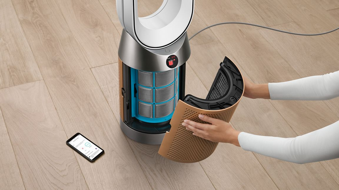 Personne retirant un filtre d'un purificateur d'air blanc et cuivré.