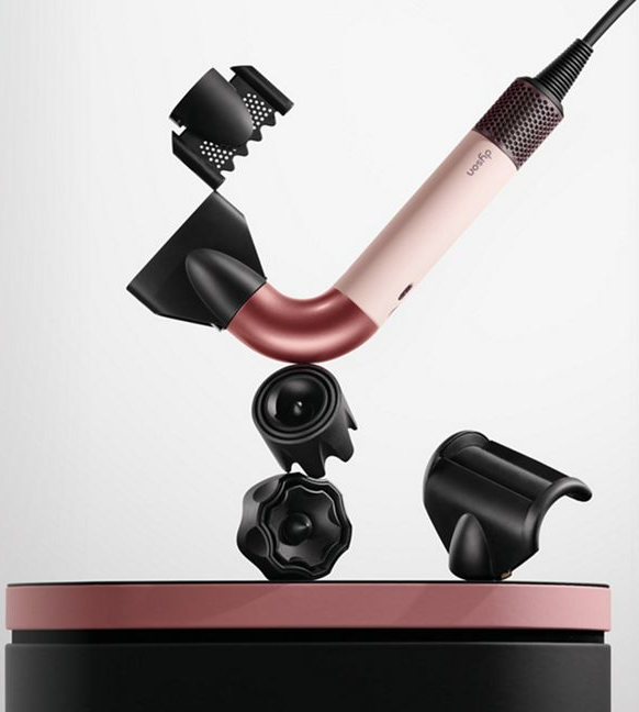 Sèche-cheveux Dyson avec plusieurs accessoires noirs, exposé sur un support.