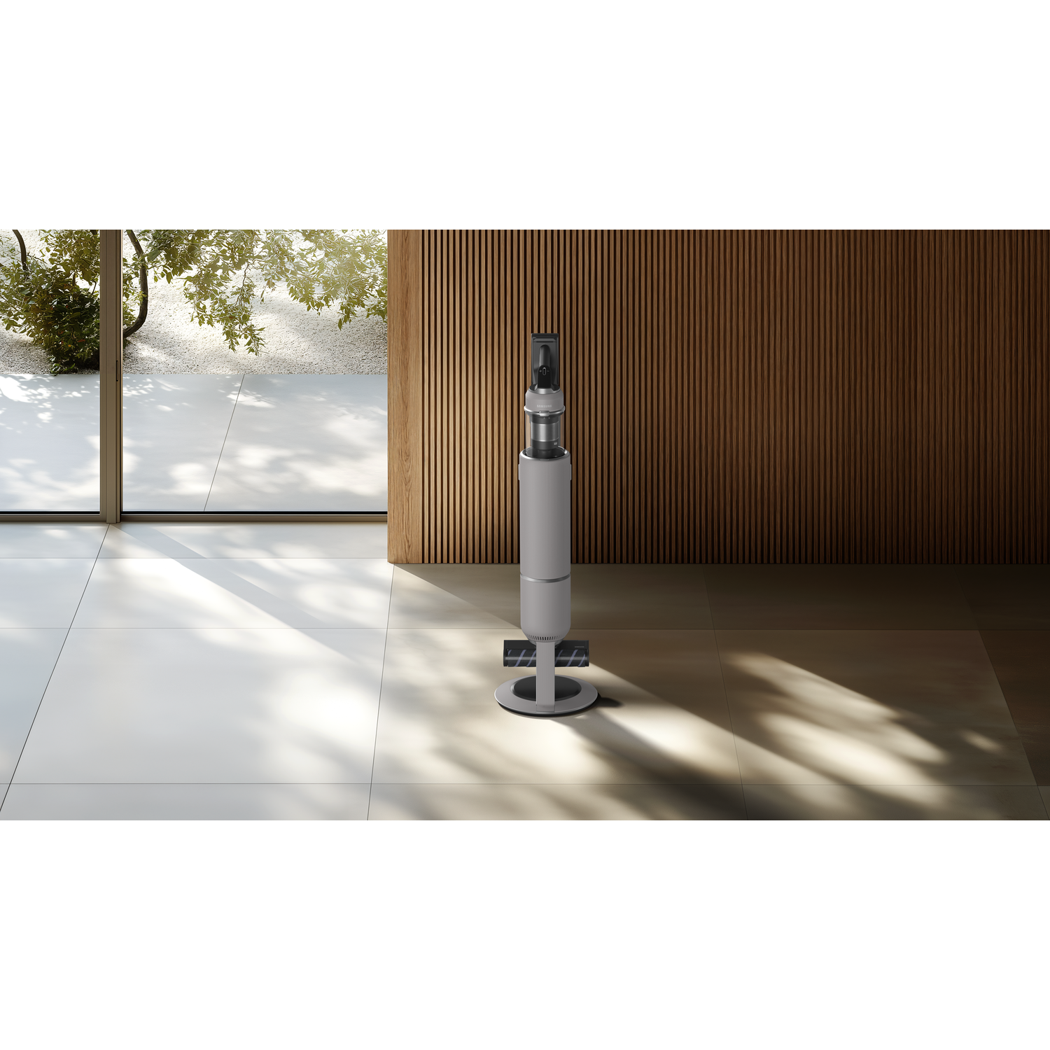 A vertical silver speaker in a room, with a window and wood paneling.