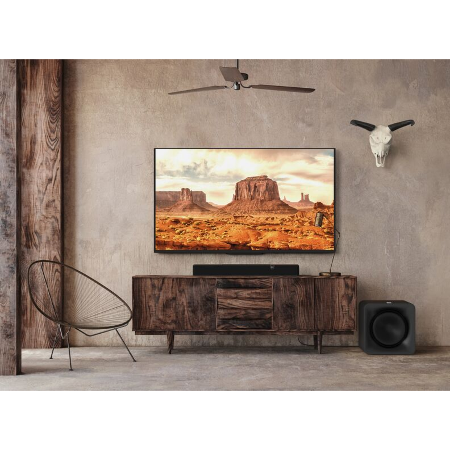 Woonkamer met een tv op een houten kast. Een soundbar staat onder de tv. Een woestijnlandschap staat op het scherm.