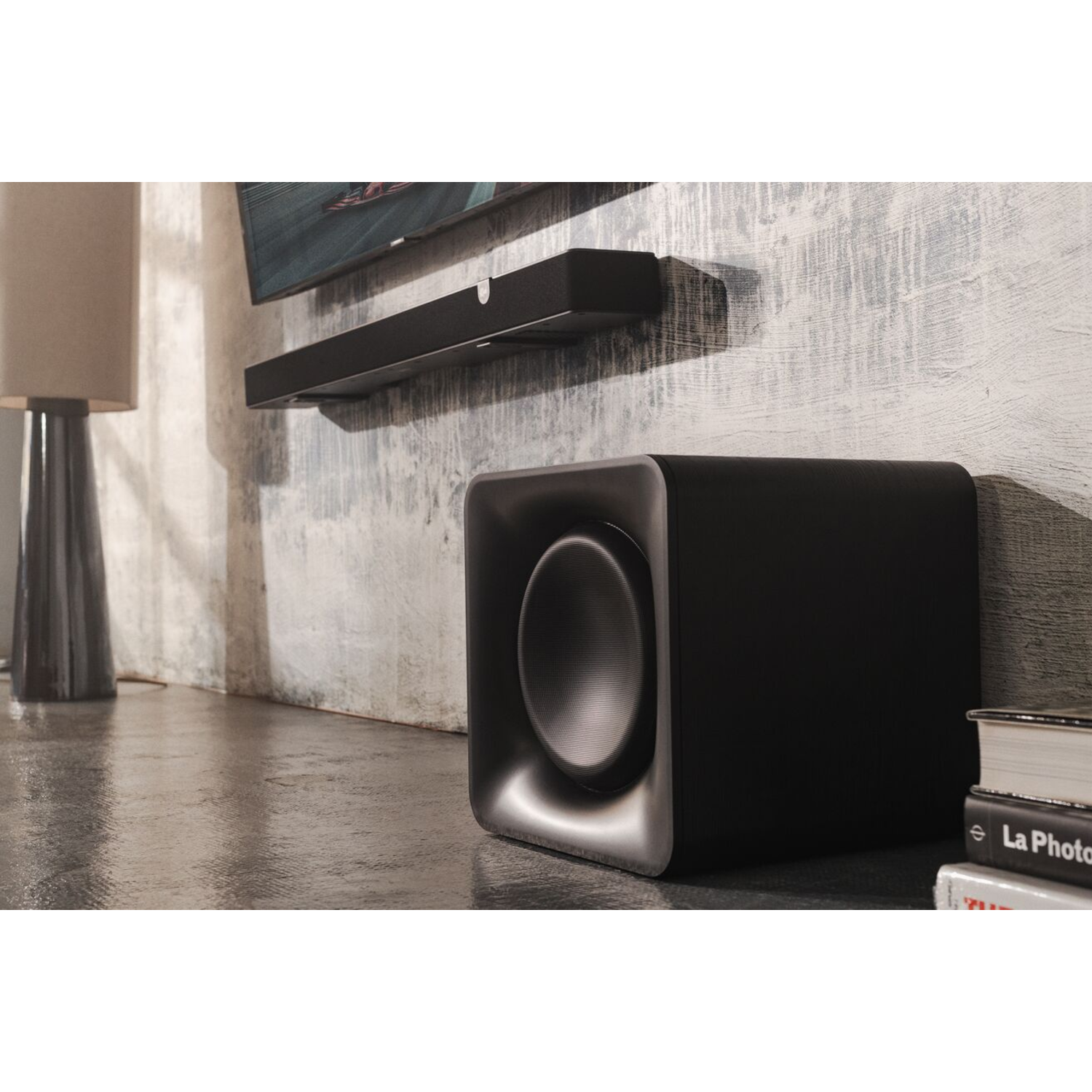 A black subwoofer next to a speaker and lamp.