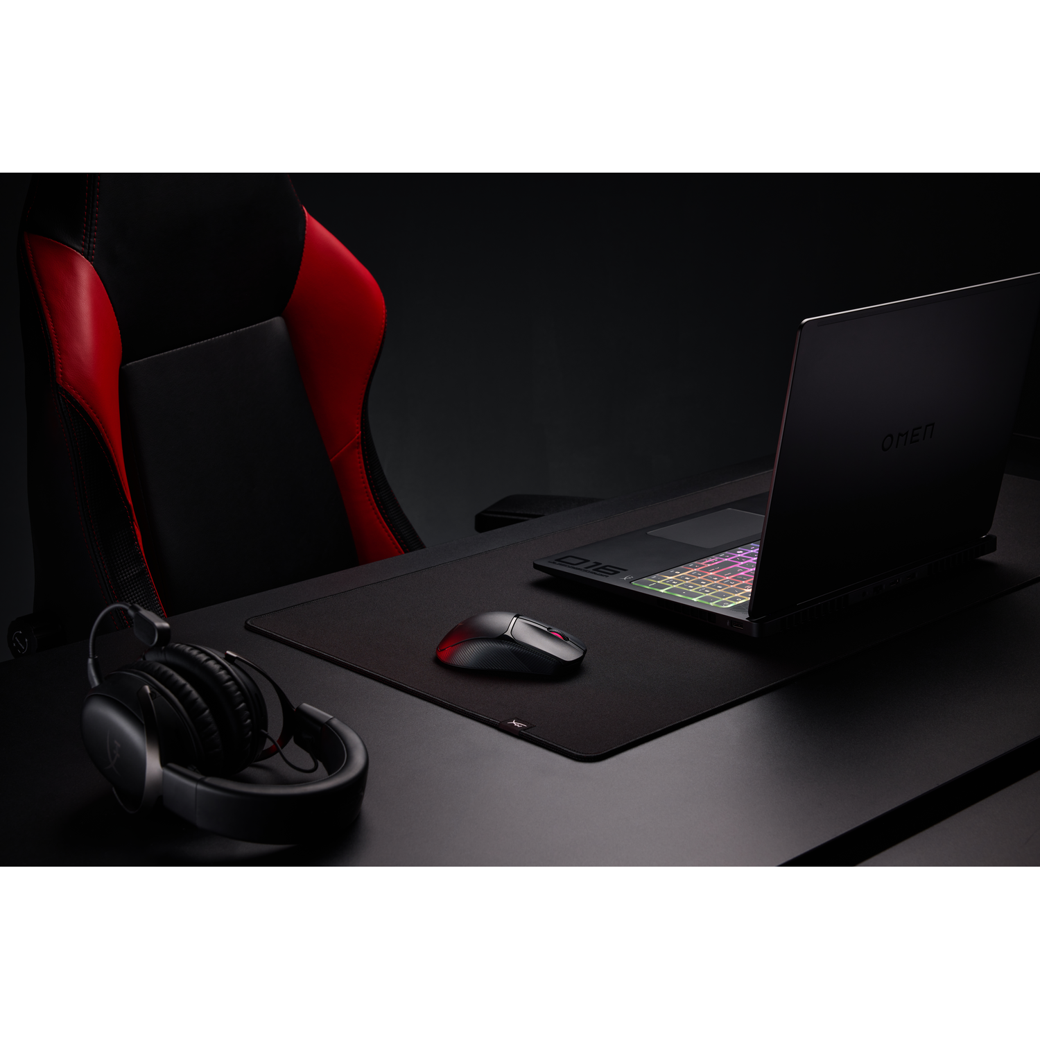 Een gaming-opstelling met een laptop, muis, koptelefoon en bureaumat.