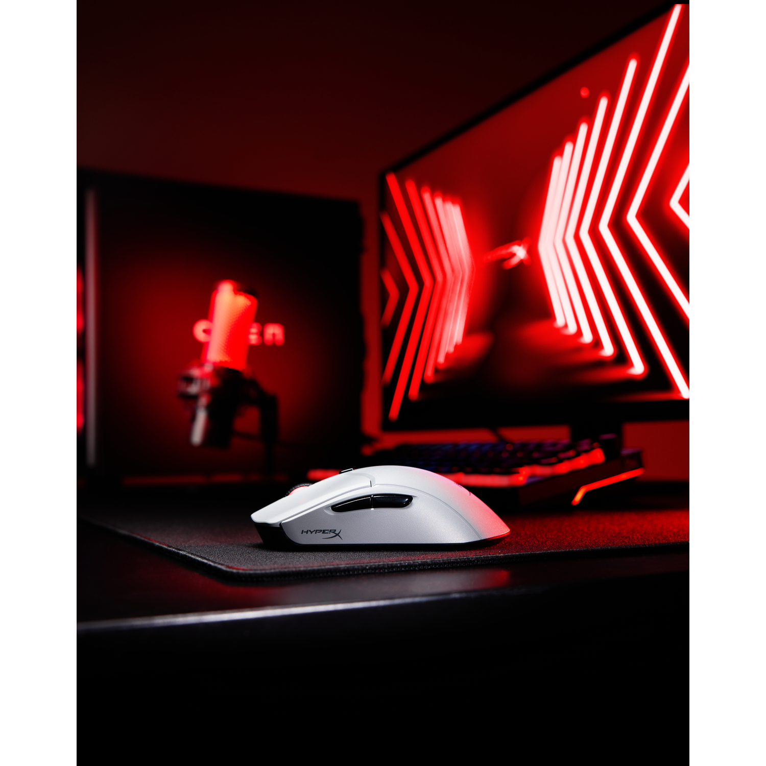 Witte HyperX gamingmuis op een zwarte muismat in een rood verlichte kamer.