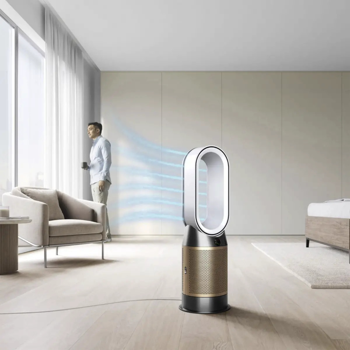 Mężczyzna stoi przy oknie, patrząc na zewnątrz. Obok niego stoi biało-złoty oczyszczacz powietrza.
