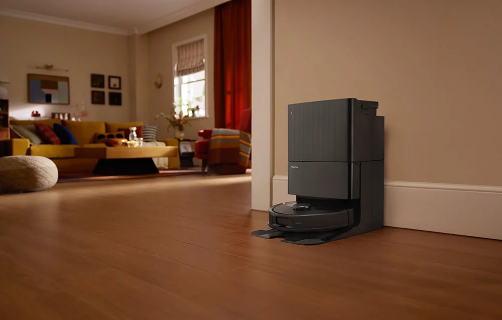 Odkurzacz robot i stacja ładująca na drewnianej podłodze w pokoju.