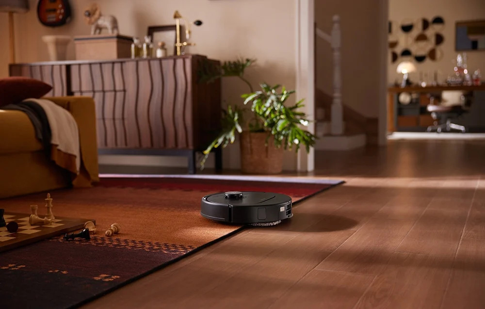 Robot sprzątający na wzorzystym dywanie w pokoju.