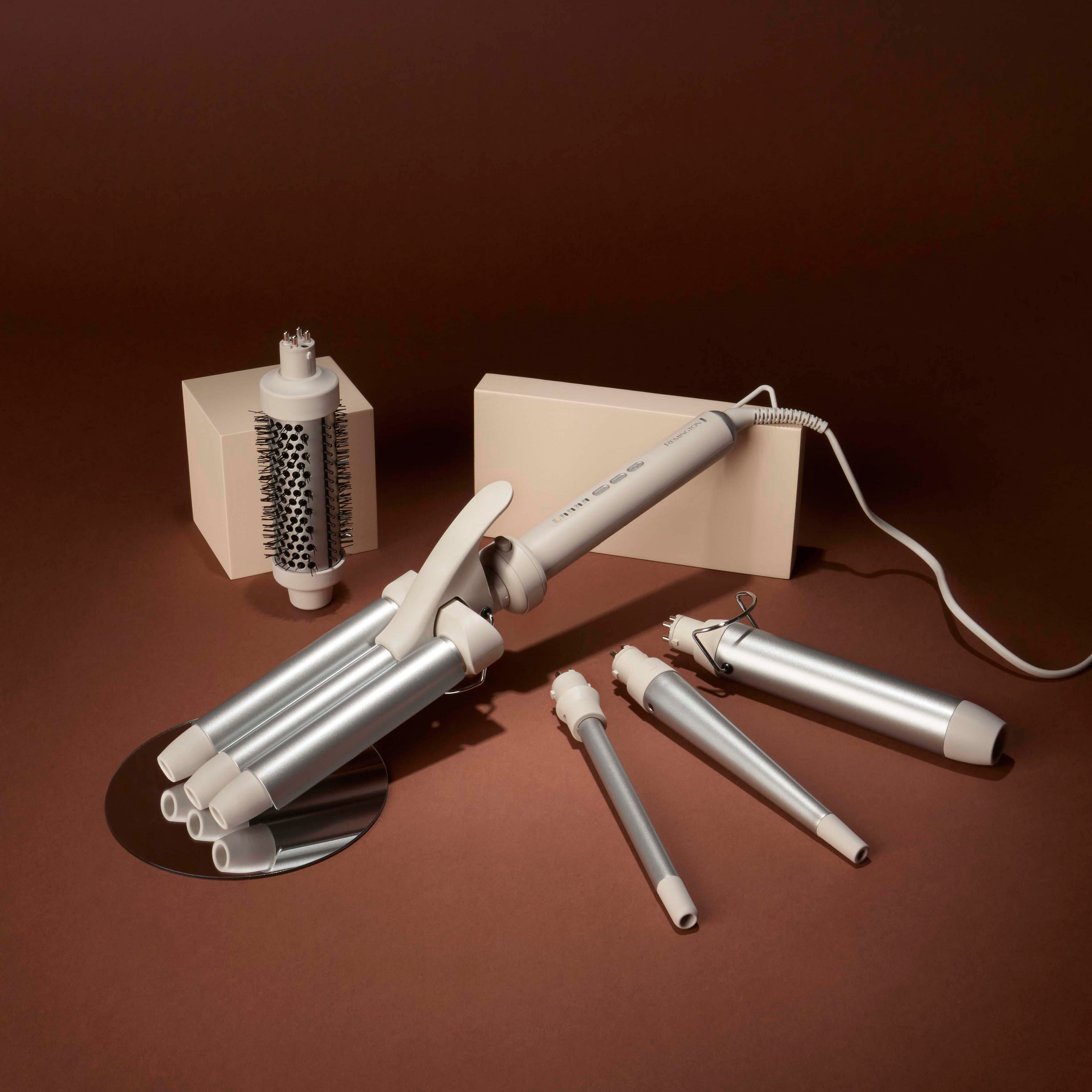 Haar-Lockenstab-Set auf brauner Oberfläche. Enthält einen Lockenstab und verschiedene Aufsätze.