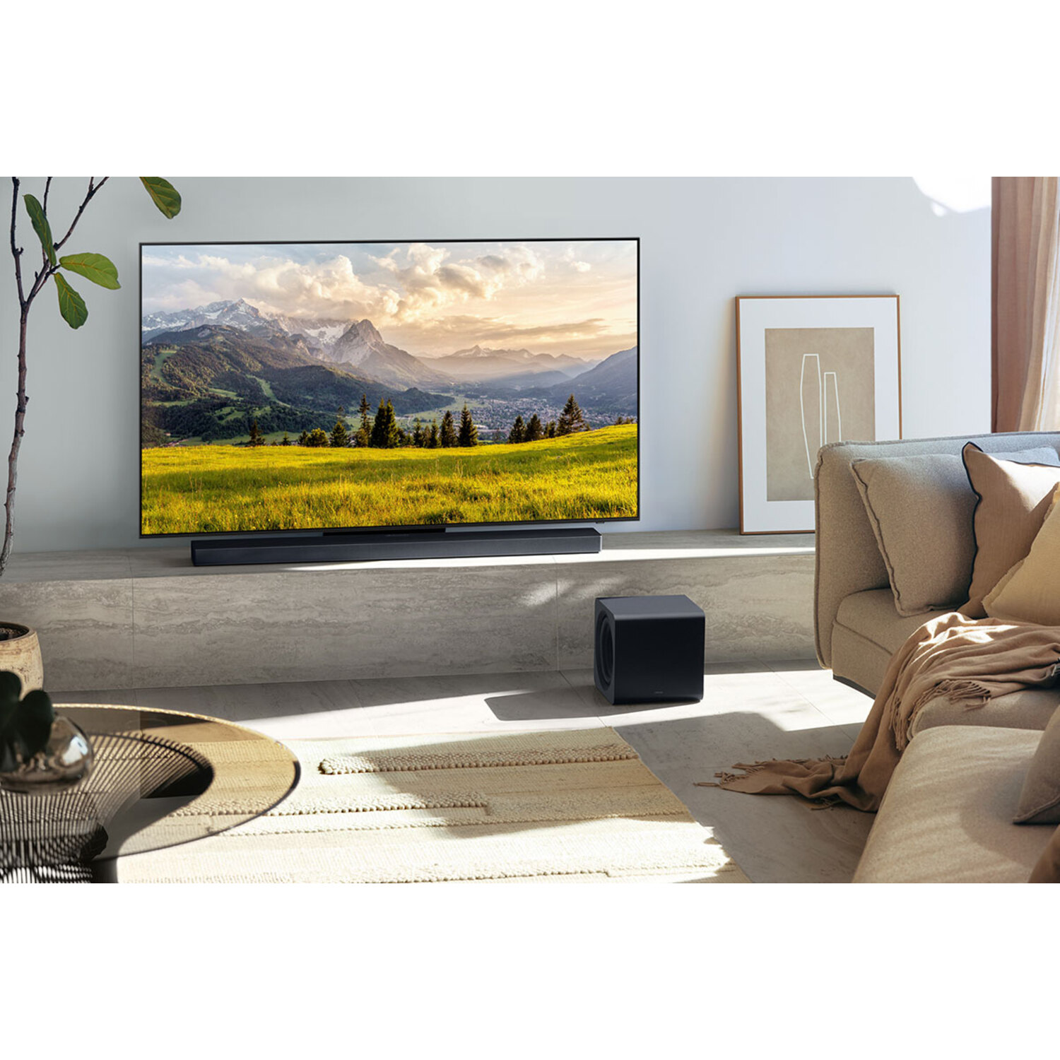 Une télévision affichant un paysage de montagne au-dessus d'une barre de son et d'un caisson.