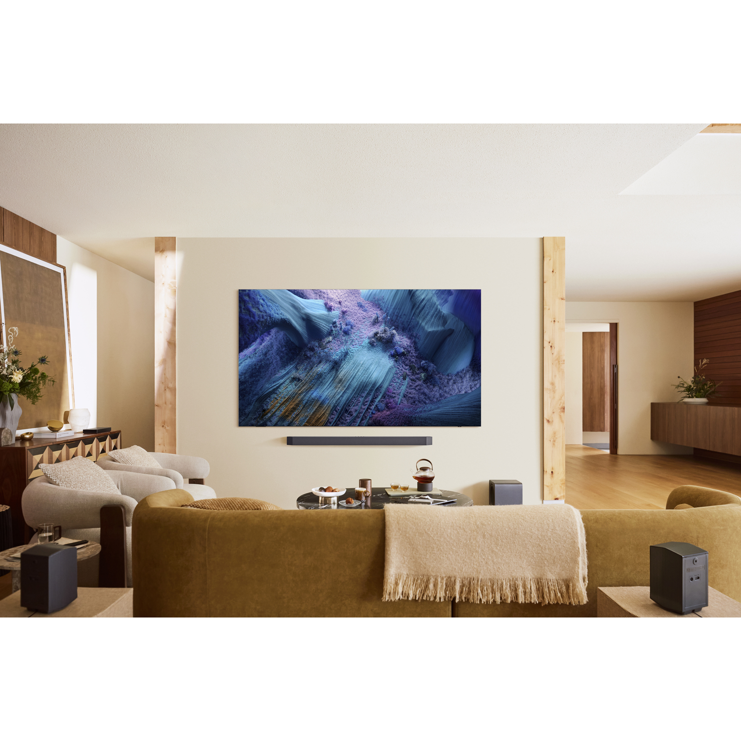 Woonkamer met grote tv met abstracte kunst, soundbar, luidsprekers en bank.