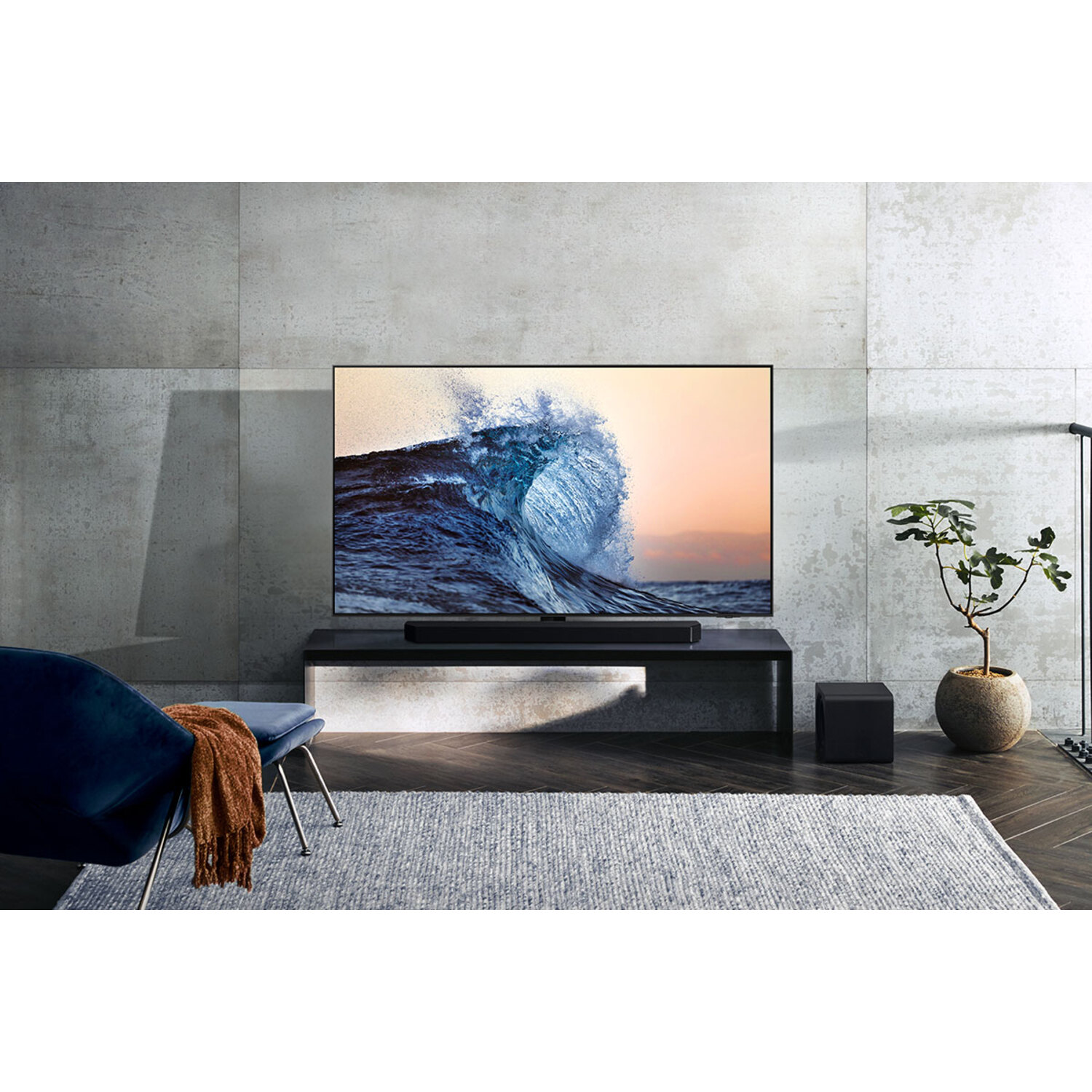 Een grote tv toont een golf. Een soundbar staat eronder. Een blauwe stoel en een vloerkleed zijn te zien.