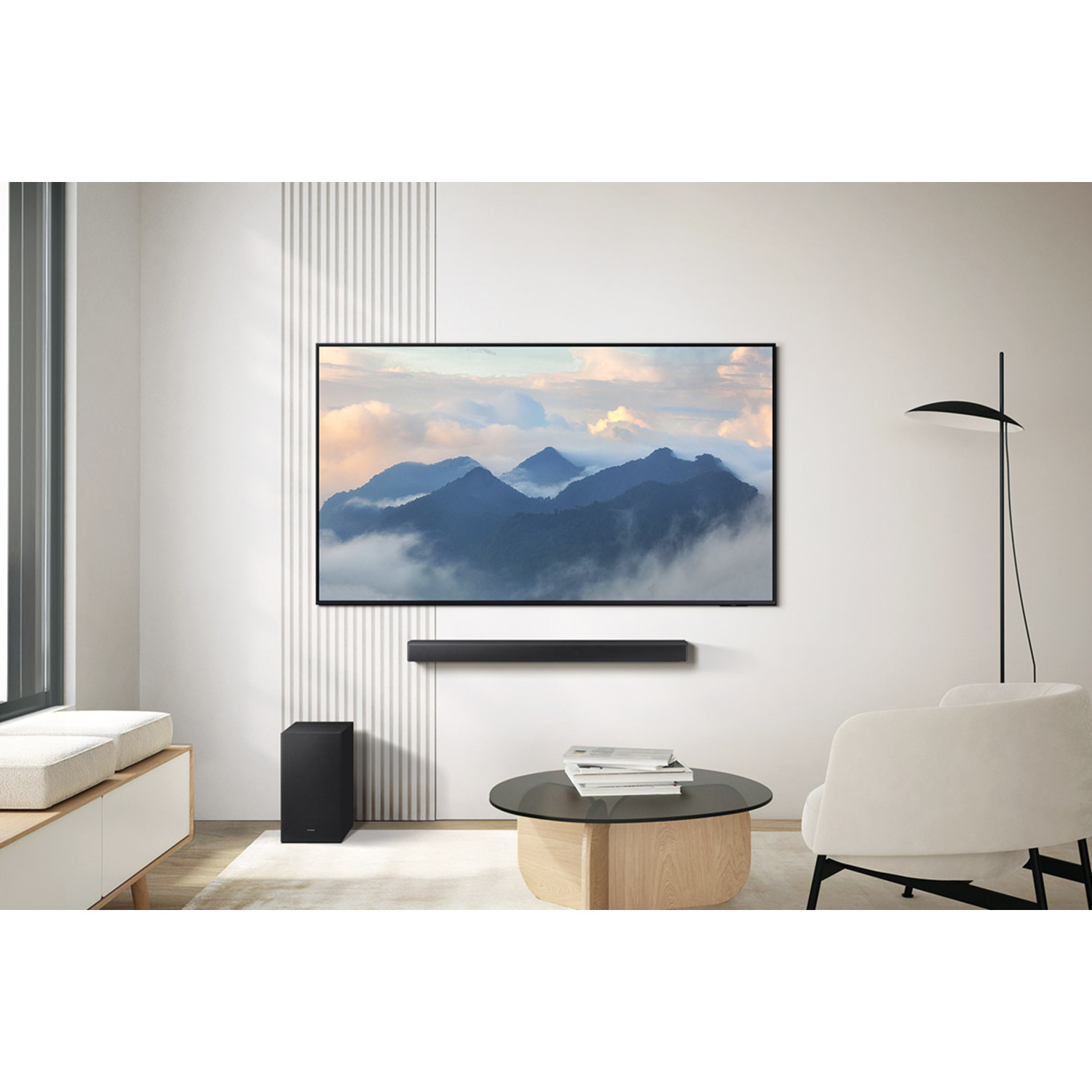 A TV showing mountains, soundbar mounted below, subwoofer below, and a modern room.