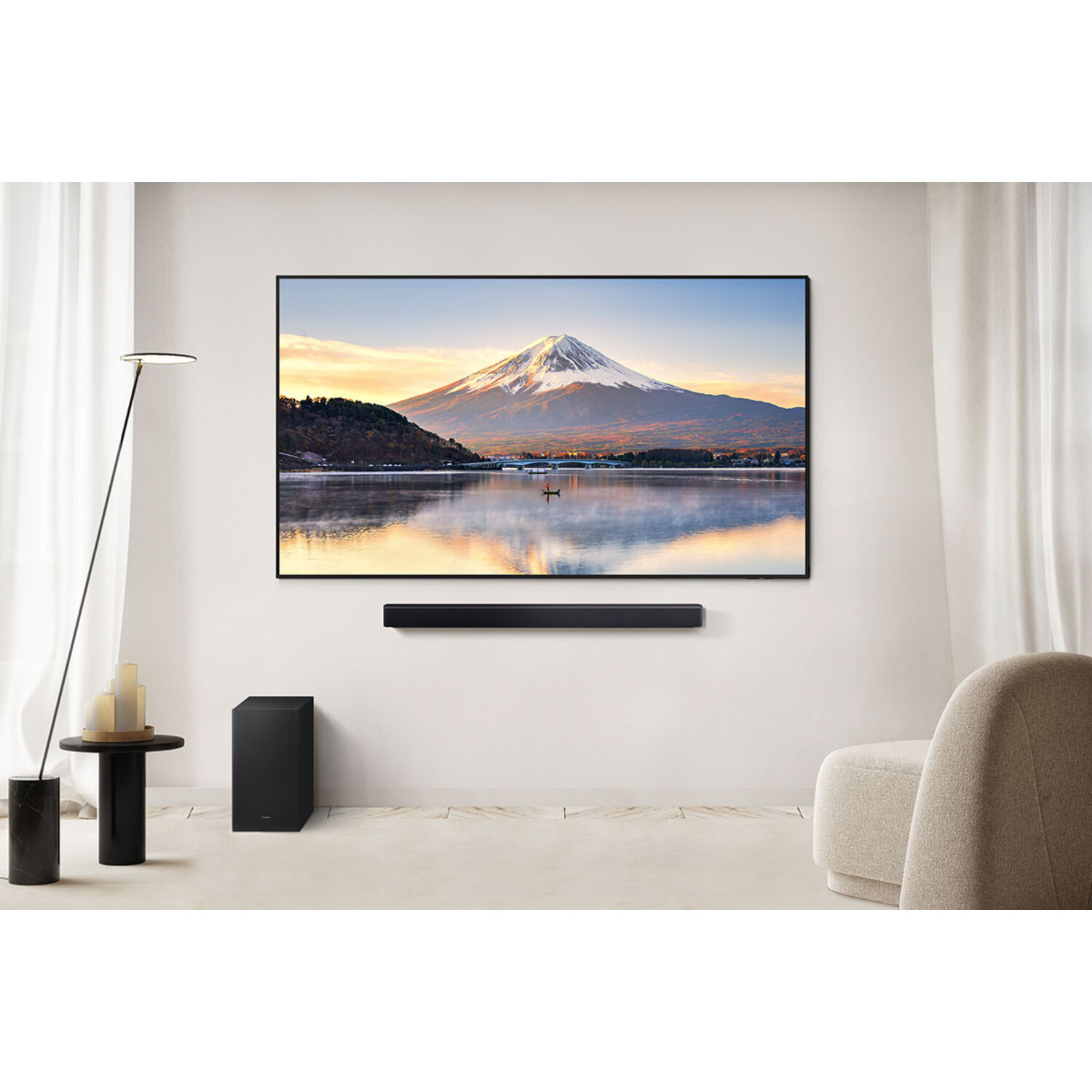 Een tv toont een berglandschap. Een soundbar en subwoofer staan eronder.