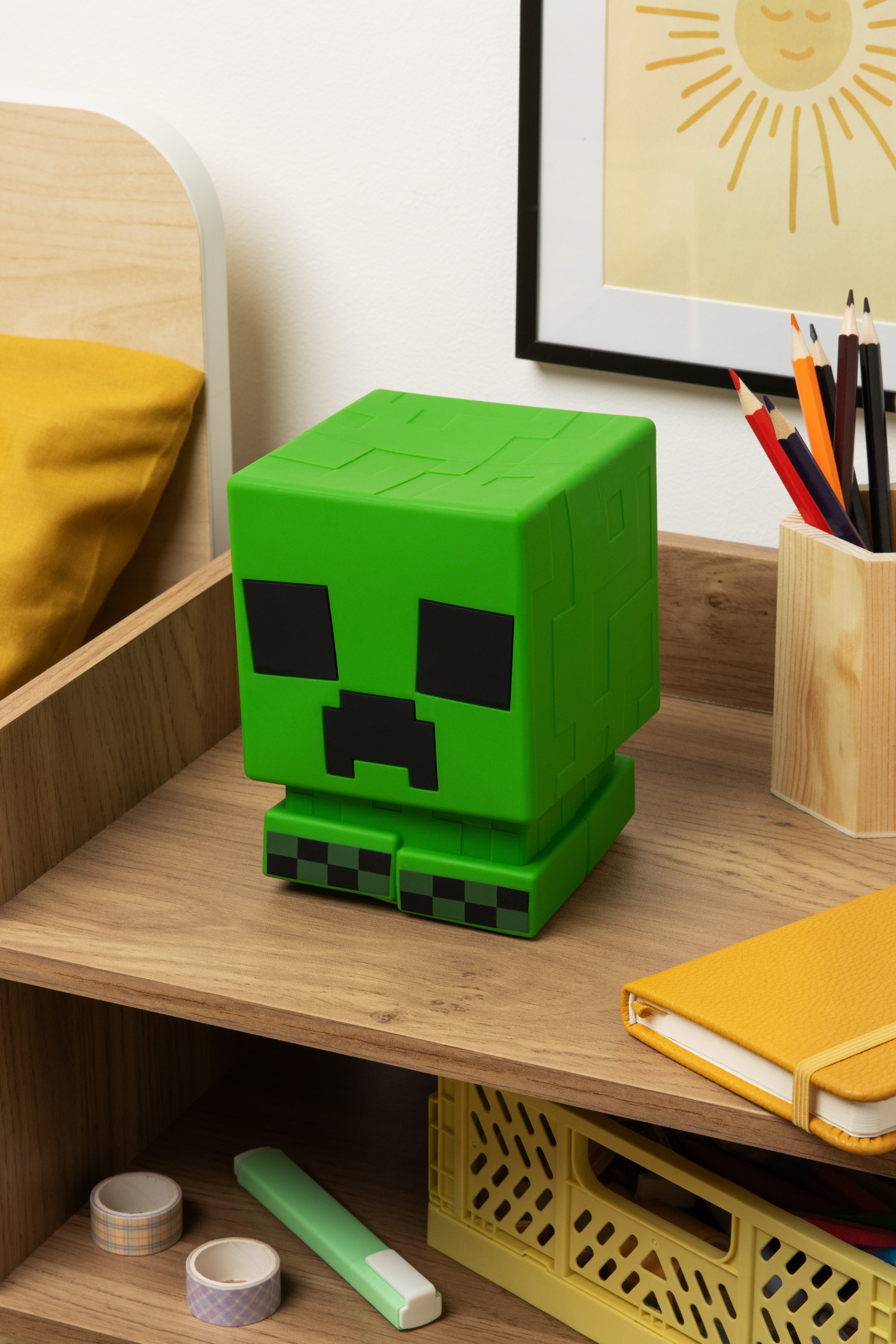 Eine grüne Minecraft Creeper Lampe auf einer Holzoberfläche. Sie hat schwarze Augen und einen Mund.