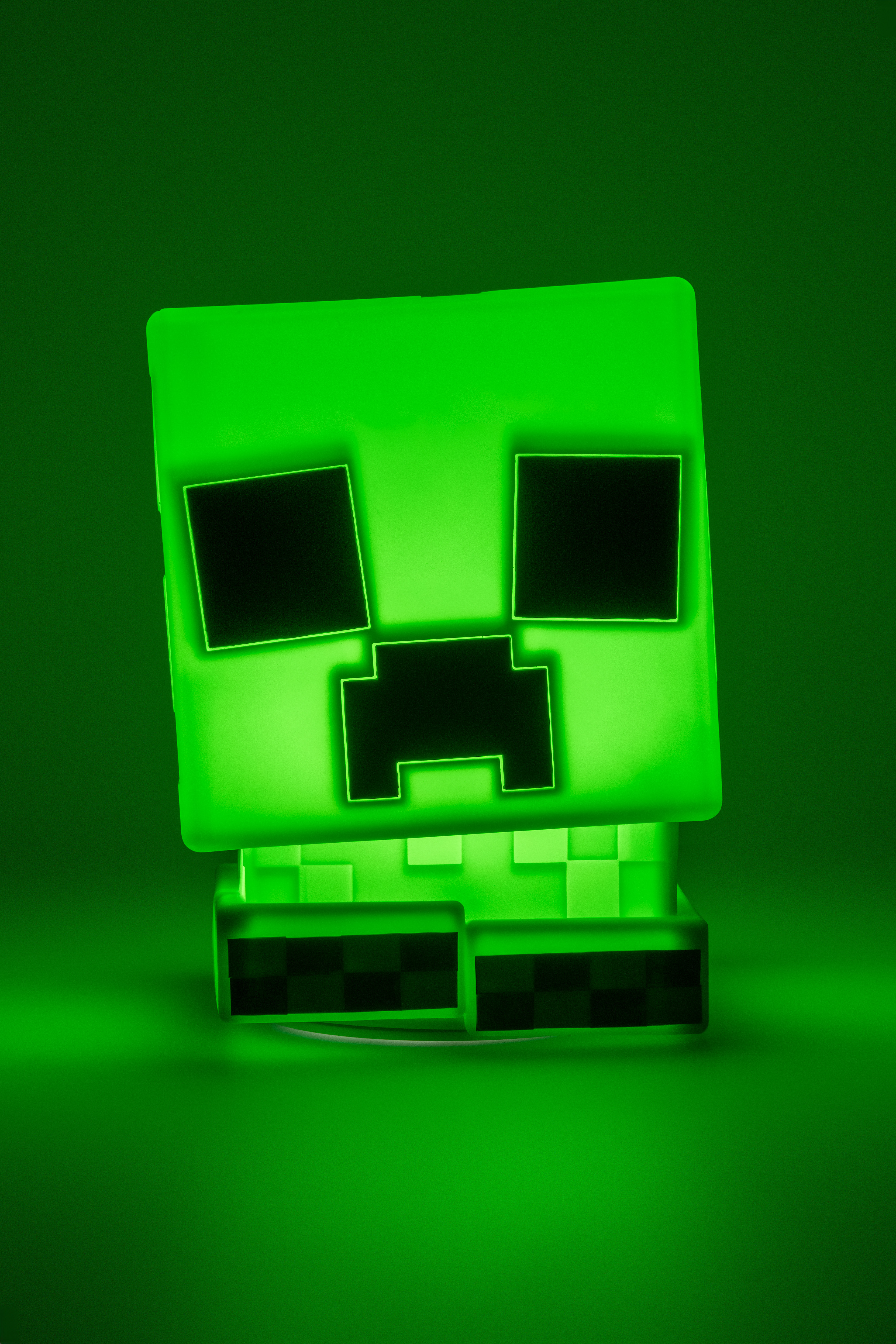 Eine grüne Minecraft Creeper Lampe. Sie hat quadratische Augen, Mund und einen blockartigen Kopf und Körper.
