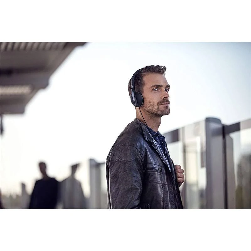 Hombre con auriculares, chaqueta de cuero, mirando a la derecha, en espacio público.