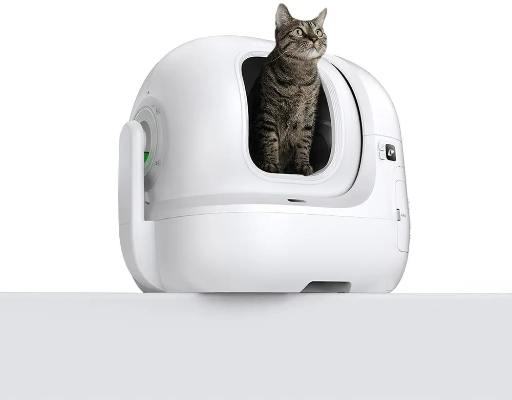 Bac à litière automatique blanc pour chat avec un chat assis à l'intérieur. Le chat est marron et noir.