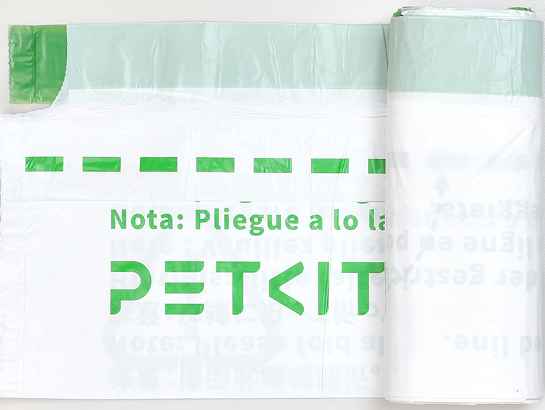 Eine Rolle weißer PETKIT-Müllbeutel mit grünem Streifen und Text auf Spanisch und Chinesisch.