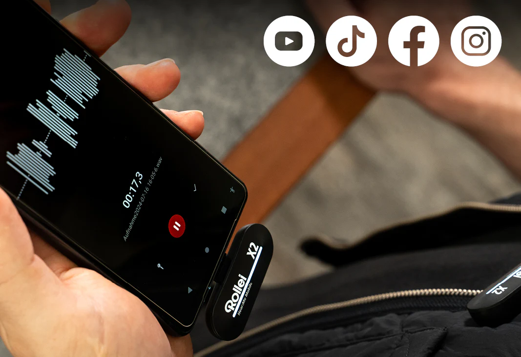 Une personne tenant un smartphone connecté à un appareil d'enregistrement audio noir.