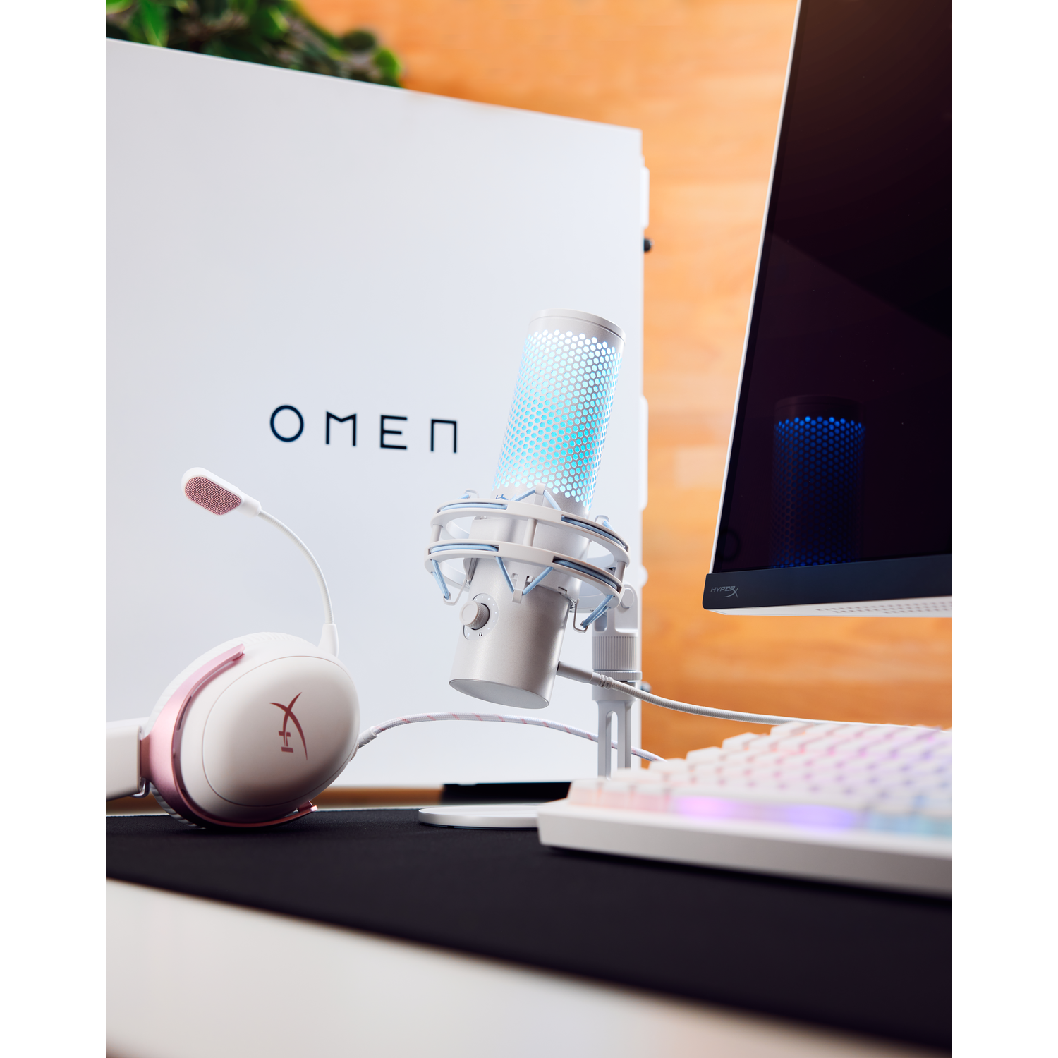Gaming setup met headset, microfoon en monitor. De microfoon heeft blauwe lampjes.