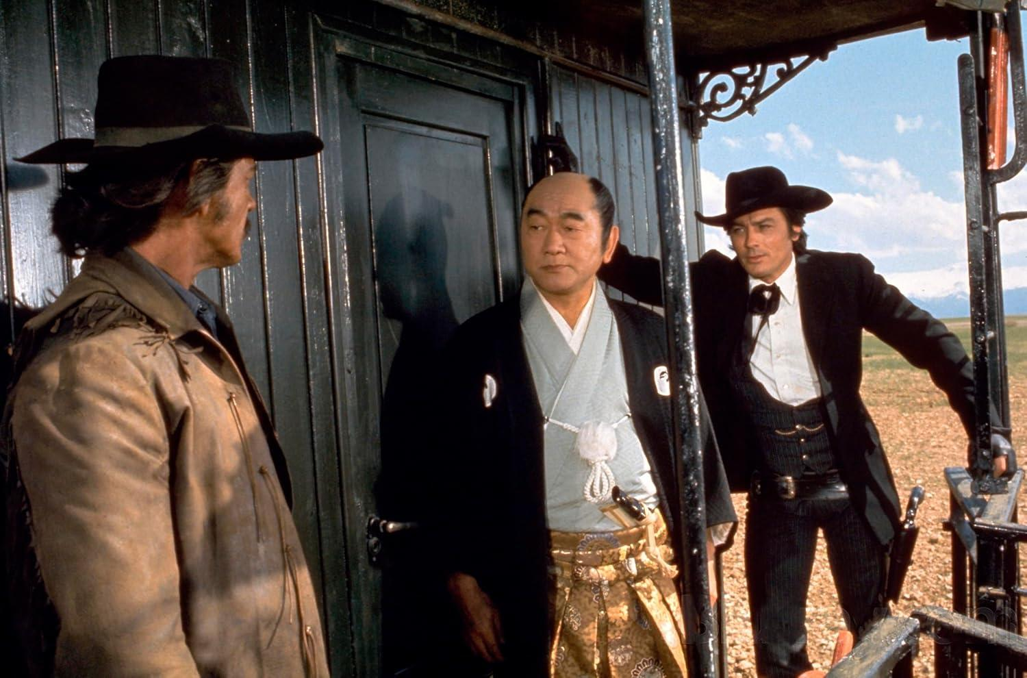 Szene aus einem Westernfilm. Drei Männer in historischer Kleidung auf einem Bahnsteig.