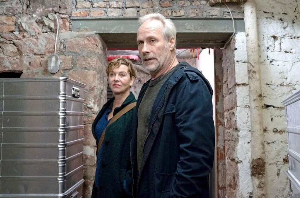 Ein Mann und eine Frau stehen in einem Backsteinraum und schauen sich an.