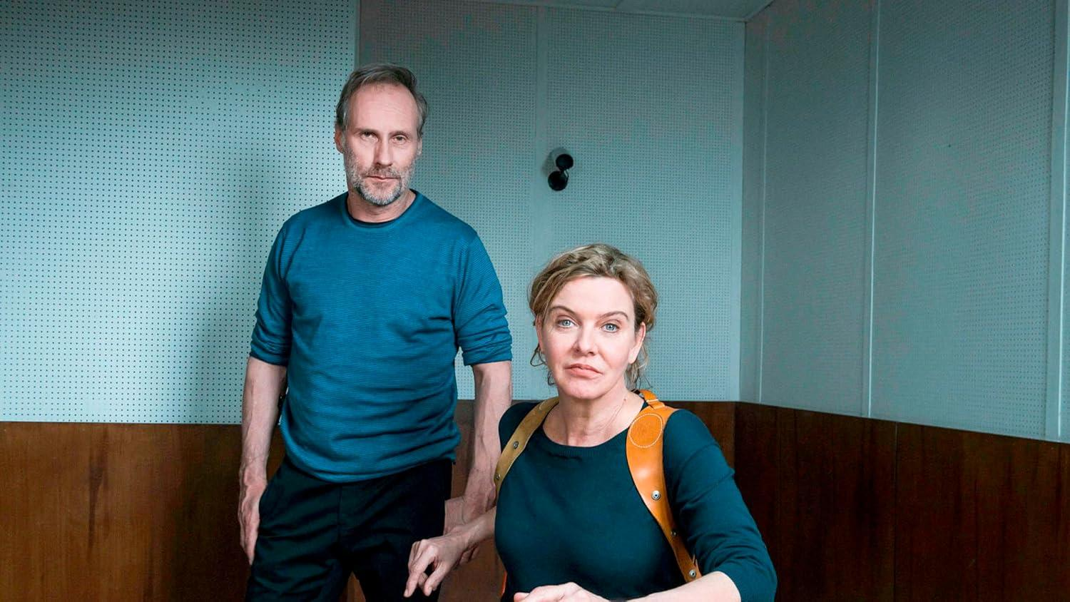 Ein Mann und eine Frau stehen in einem Raum mit blauen Wänden und schauen nach vorne.