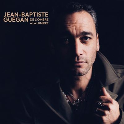 Portrait d'un homme, visage à moitié éclairé, texte : Jean-Baptiste Guegan, De l'Ombre à la Lumière. Fond sombre.