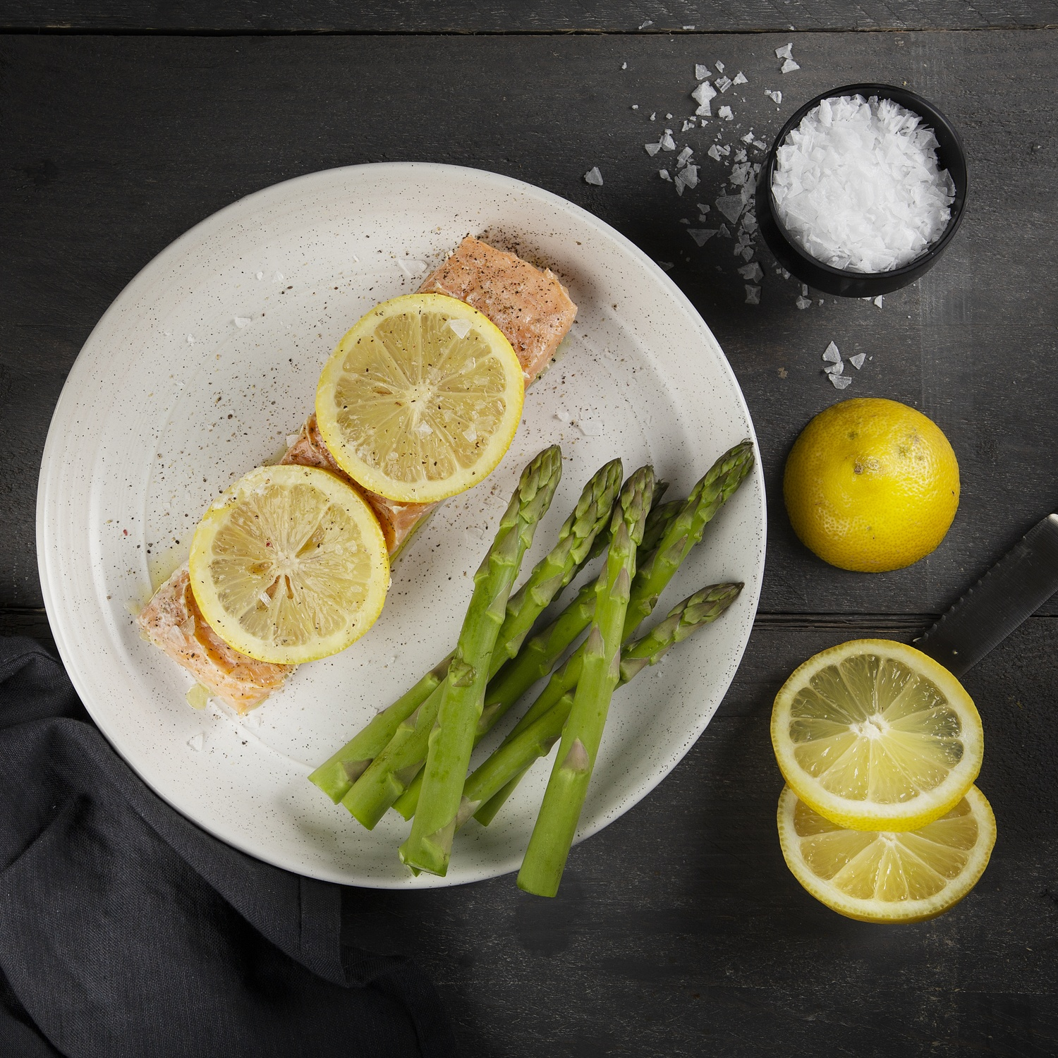 Piatto con salmone, fette di limone e asparagi. Sale e fette di limone a lato.