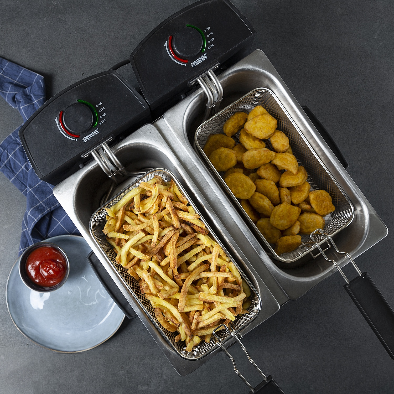 Friggitrice doppia con patatine e nuggets, una ciotola di ketchup e un tovagliolo blu.
