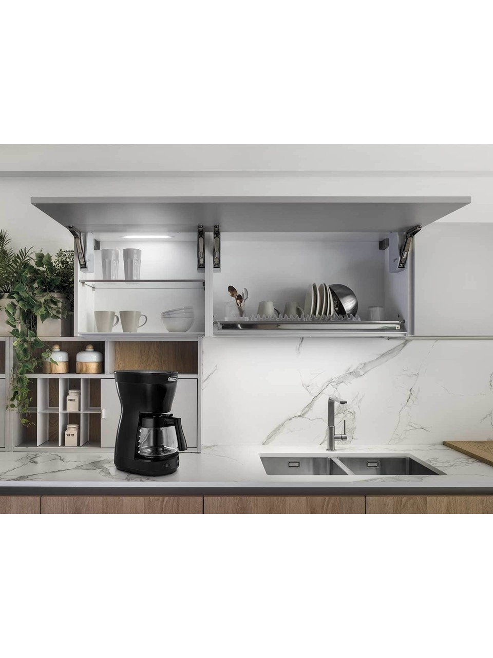 Kahve makinesi, lavabo ve açık dolaplı mutfak. Tabaklar ve fincanlar görülebilir. Mermer tezgah ve backsplash.