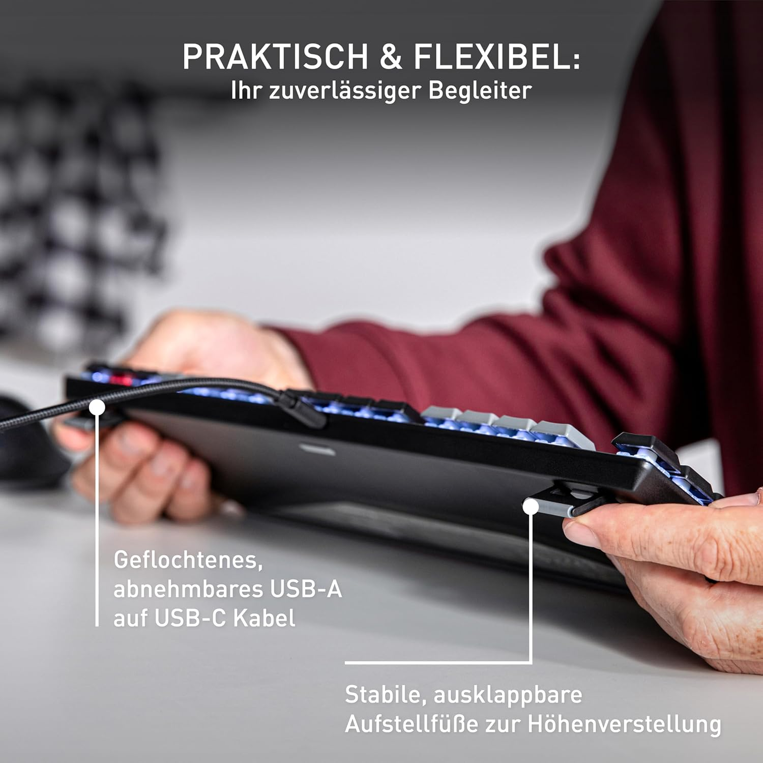 Hände halten eine schwarze Tastatur mit weißen Tasten. Die Tastatur hat ein USB-A-Kabel.